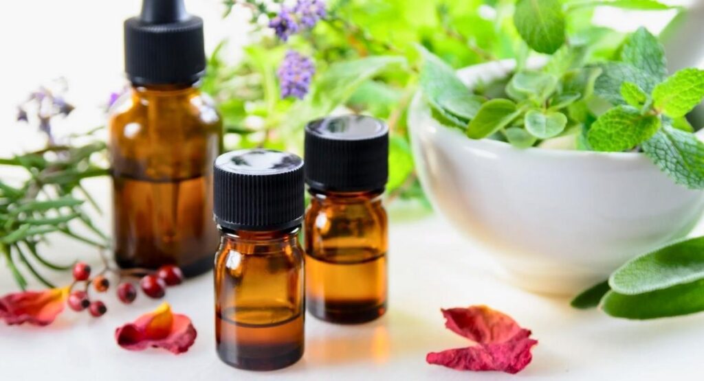 Frascos de óleos essenciais ao lado de plantas e flores, em ambiente natural e acolhedor, simbolizando aromaterapia e bem estar. Florais de Bach ansiedade